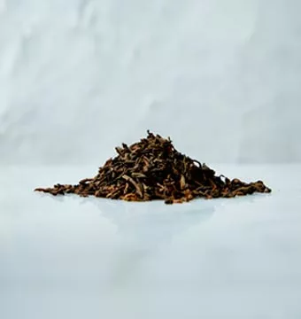 A heap of dark brown Pu-Erh tea Leaves on a marbled surface